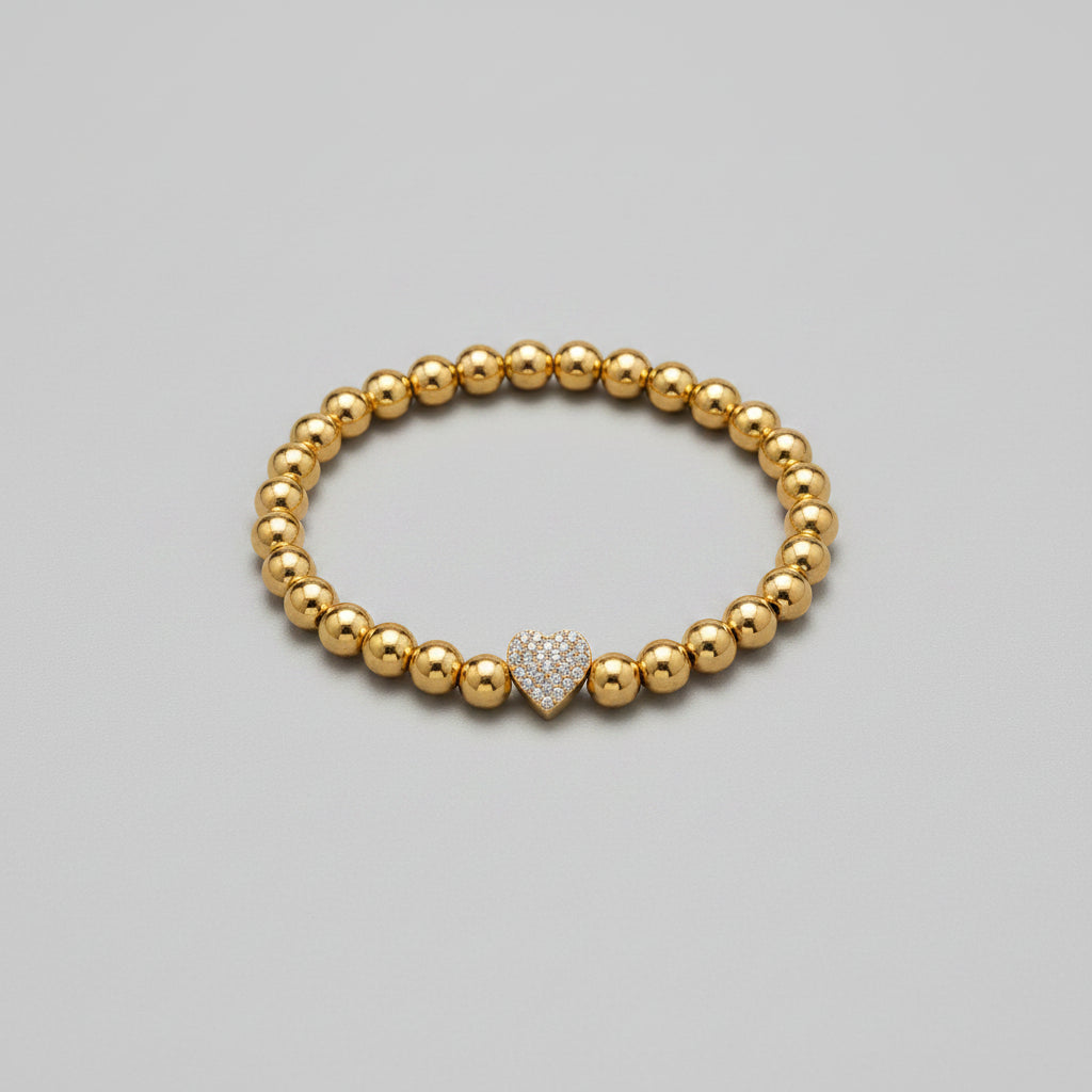 Gold beaded bracelet with a heart-shaped clasp on a white background