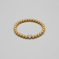Gold beaded bracelet with a heart-shaped clasp on a white background